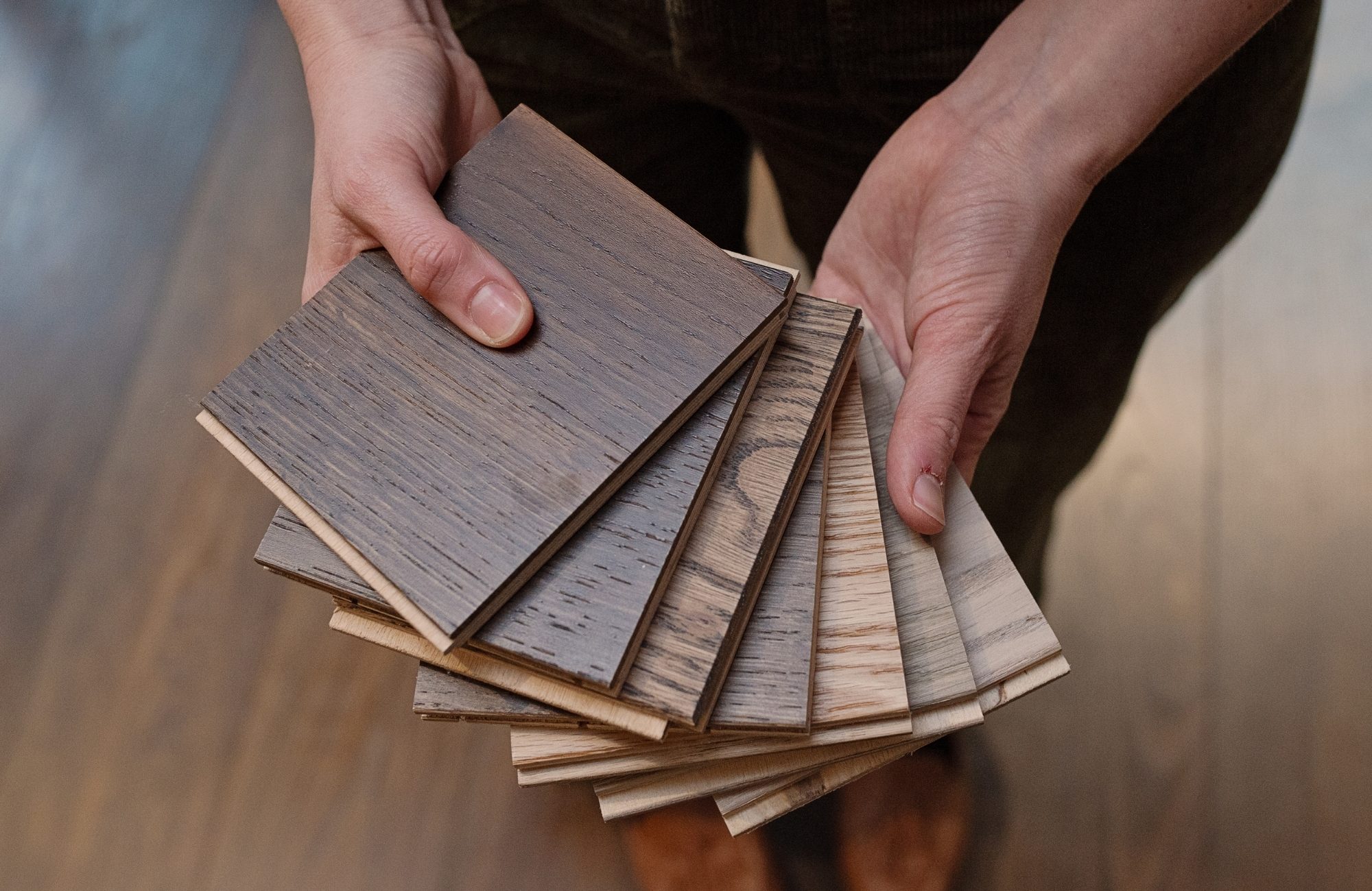 Havwoods hardwood sample boards - Kirkpatrick Floors Hands fanning Havwoods hardwood sample boards, each cut edge showing the top wood layer over the core