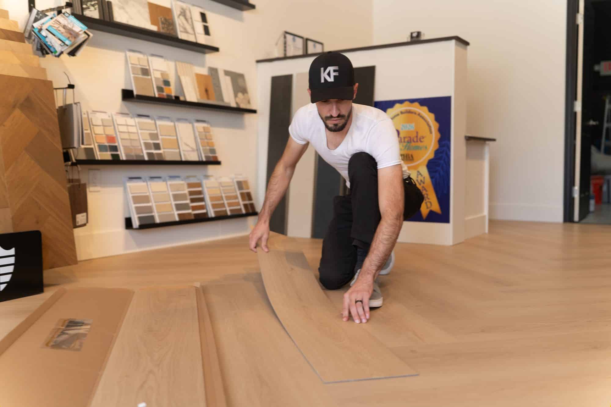 Kirkpatrick Floors plank installation in the showroom - Kirkpatrick Floors Kyler Kirkpatrick laying a light oak-look plank on the floor of the Kirkpatrick Floors showroom in Bunnell