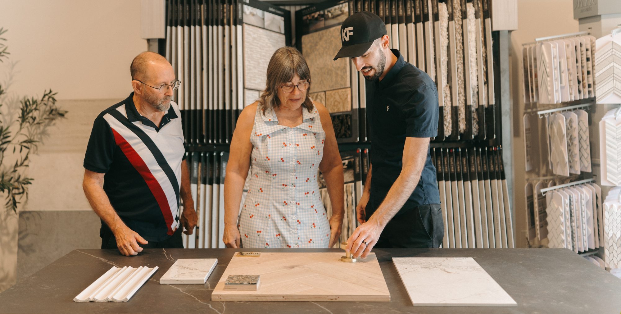 Kirkpatrick Floors tile consultation in the showroom - Kirkpatrick Floors Kyler Kirkpatrick comparing tile samples with two customers at the Kirkpatrick Floors showroom in Bunnell