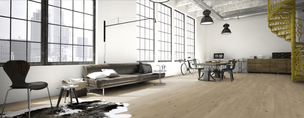 Loft apartment with large industrial windows, a brown sofa, dining table, bicycles, a yellow spiral staircase, and wooden floors. Modern and minimalistic decor with city skyline visible outside.