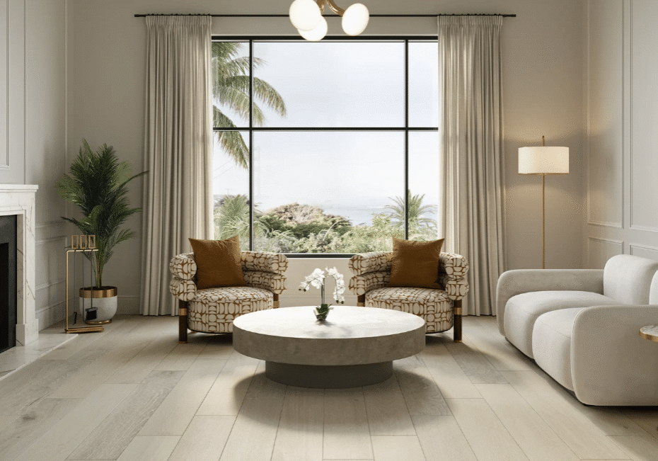 Modern living room with a marble fireplace, two patterned armchairs, a white sofa, a round coffee table, potted plants, and large window showing palm trees and sky. Neutral tones and gold accents decorate the space.